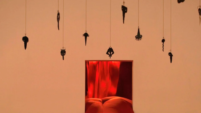 werk van Annette Messager getiteld Casino. hangende kleine objecten met rode voorgrond
