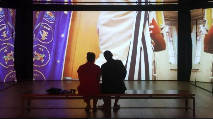 beeld van het ANU museum met twee mensen die voor lichtbeelden zitten