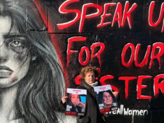muurschildering met vrouw in zwart wit en rode letters Speak Up for Our Sisters